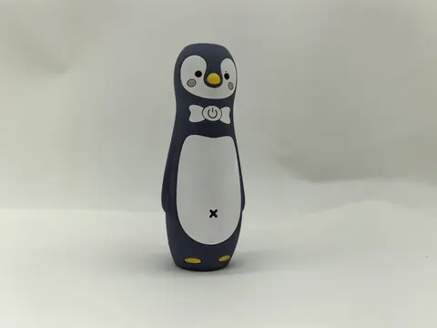 Dark navy silicone figure moulded as a penguin, with a printed white belly, printed eyes and yellow moulded feet.